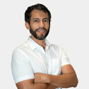 Se presenta al público general y la comunidad educativa al profesor de la Escuela de Idiomas, Giohanny Olave La foto fue tomada en primer plano, fondo blanco y el profesor está situado en el centro.