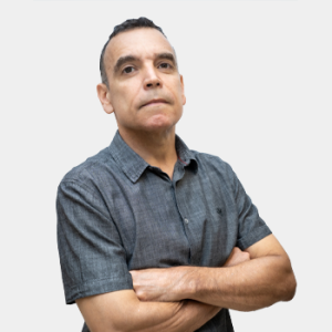 La foto fue tomada en primer plano, fondo blanco y el profesor Jhon Jairo Caceres está situado en el centro.